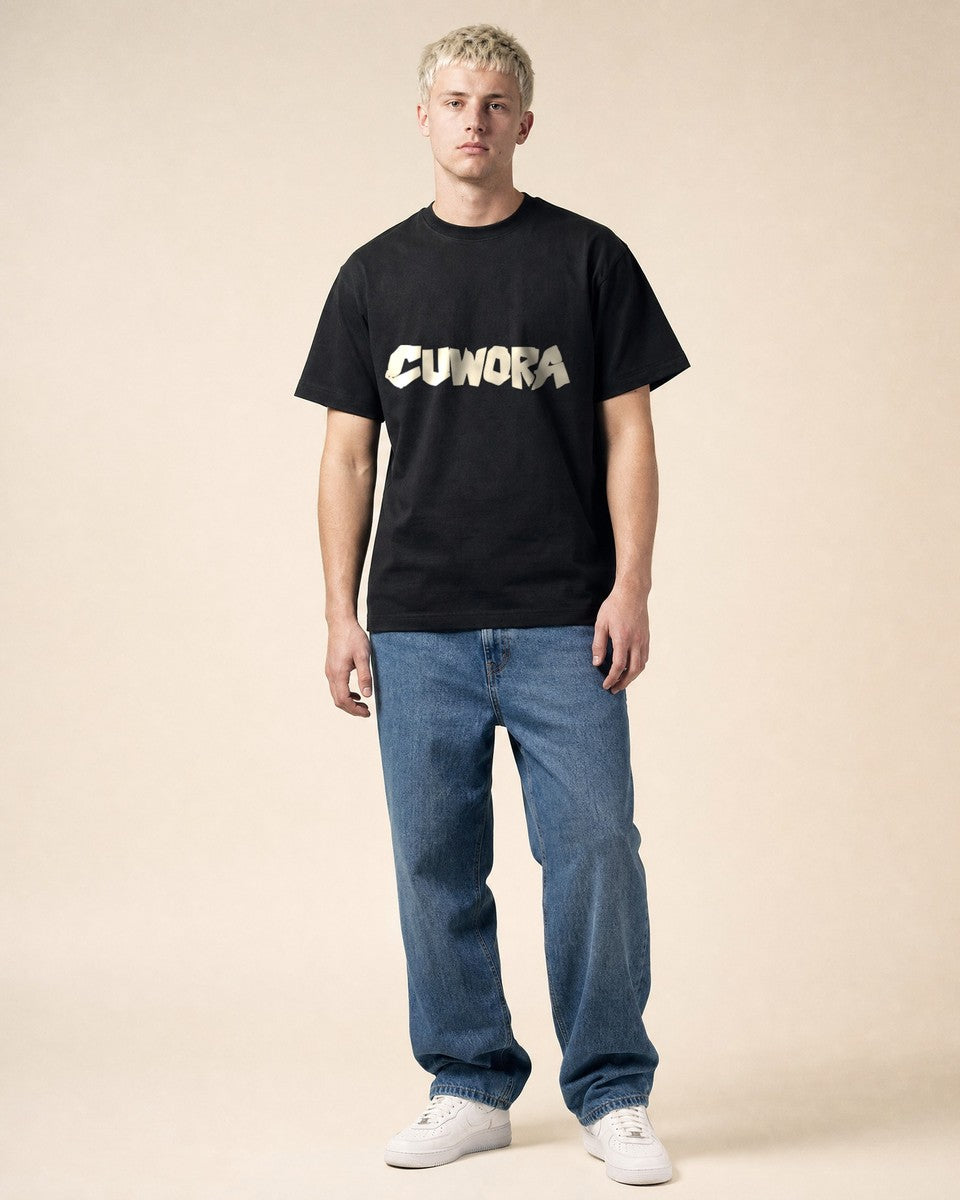 Model wearing the CUWORA Wordmark Tee in Black, front view with the bone CUWORA wordmark across the chest