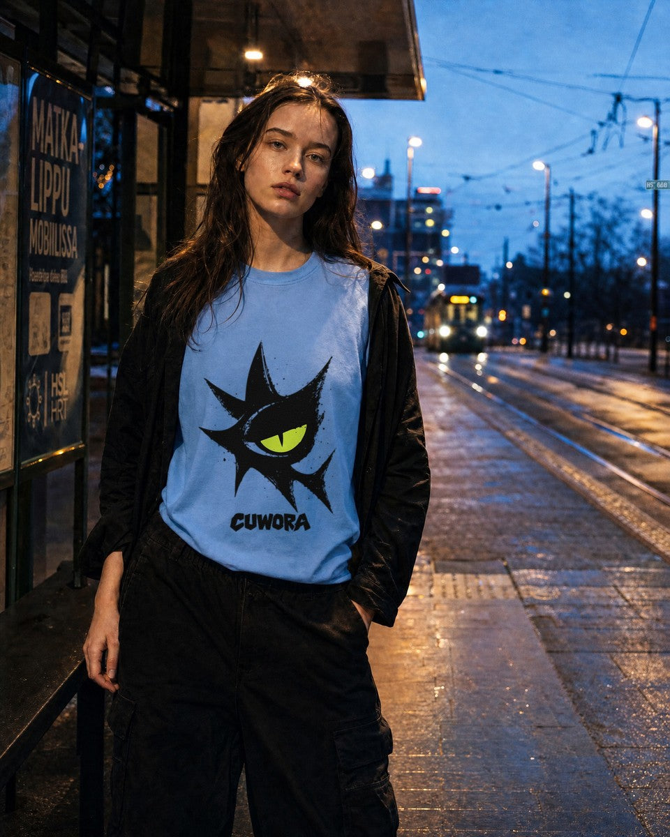 Model wearing the Signal Eye Tee in Carolina Blue at a tram stop at night, front view with the eye print